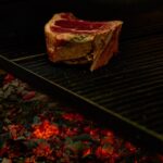 Raw steak slowly cooking on grill