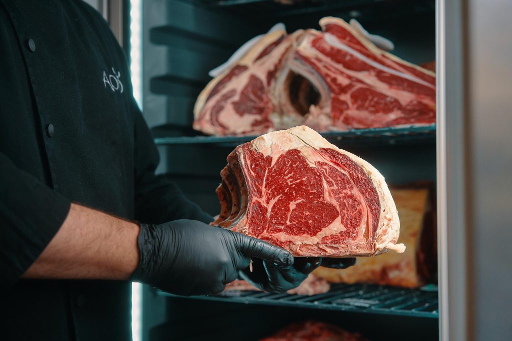 Raw beef steak held by chefs hands